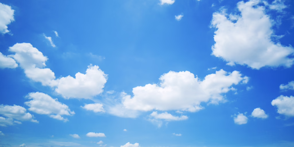 Open blue sky with a few soft white clouds in clear daylight.