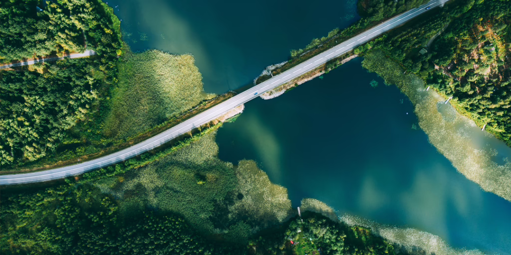 Aerial view of a bridge crossing blue water, connecting green landscapes on either shore.