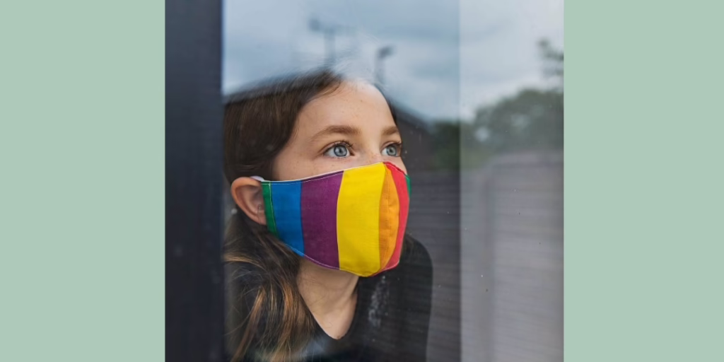 Text Veris 2020 Impact Report, image, a young girl looks out a window while wearing a fabric face mask common during the COVID-19 Pandemic with a rainbow pattern.